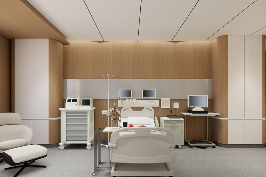 A modern hospital room maintained by medical facility cleaning services, featuring an adjustable patient bed, medical monitoring equipment, a supply cart, and a lounge chair.